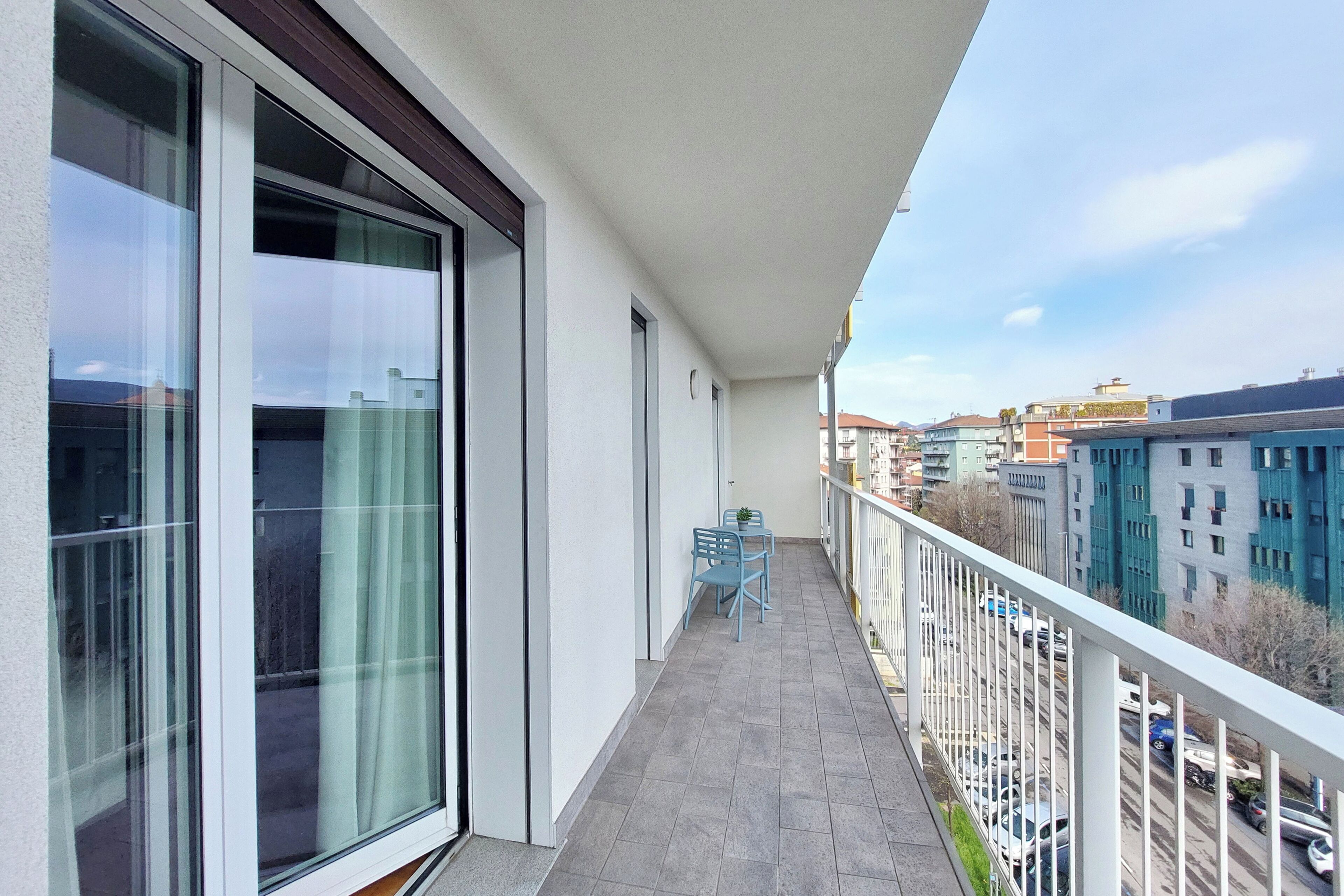 Un balcon donnant sur le paysage urbain, une petite table avec des chaises et une plante en pot.