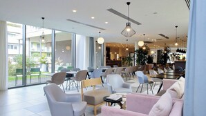 A modern hotel lobby with a mix of seating options, large windows, and contemporary lighting fixtures. -  Quarto Verde Apartments (Bergamo)