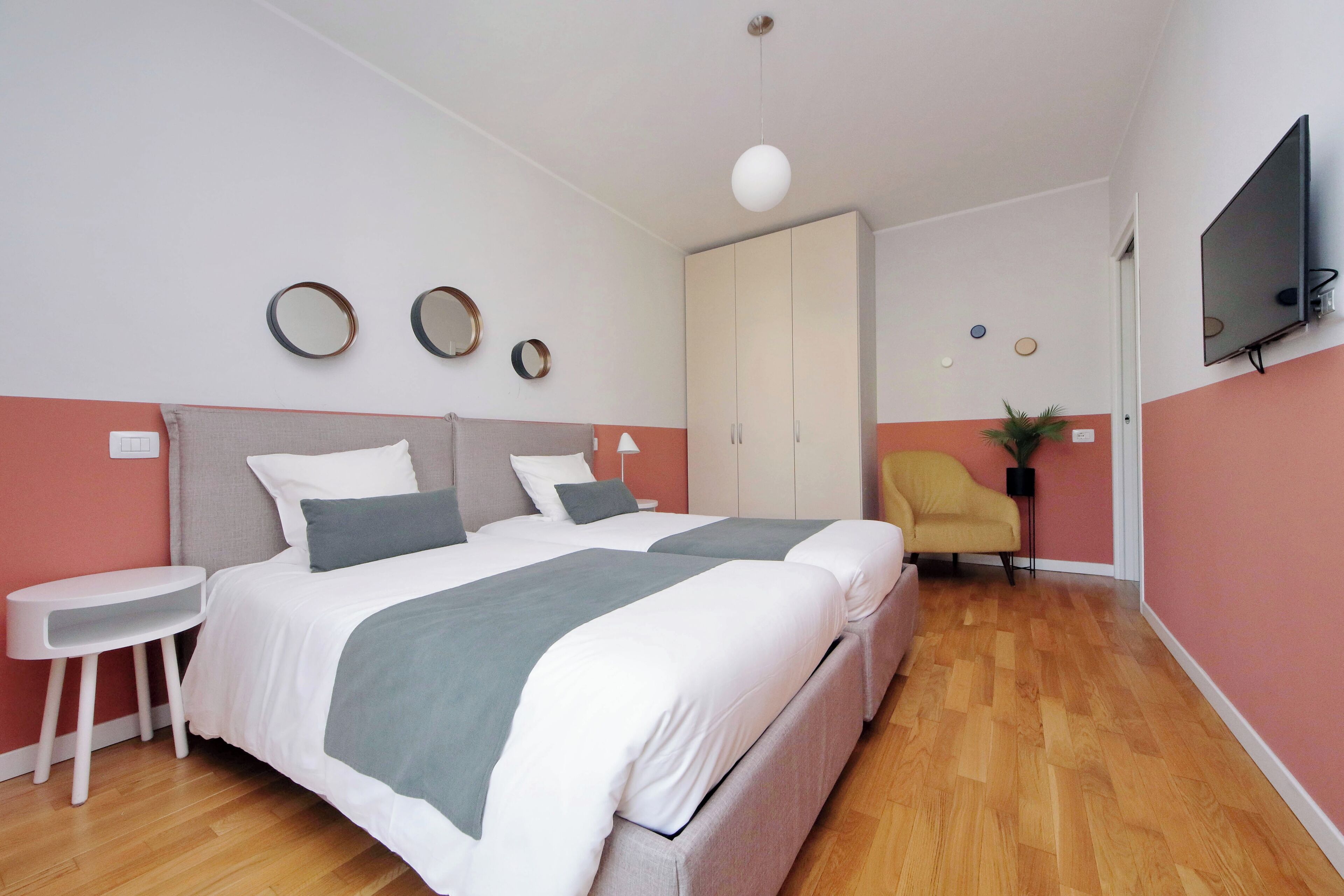 A bedroom with two beds, a TV, a wardrobe, and a small table.