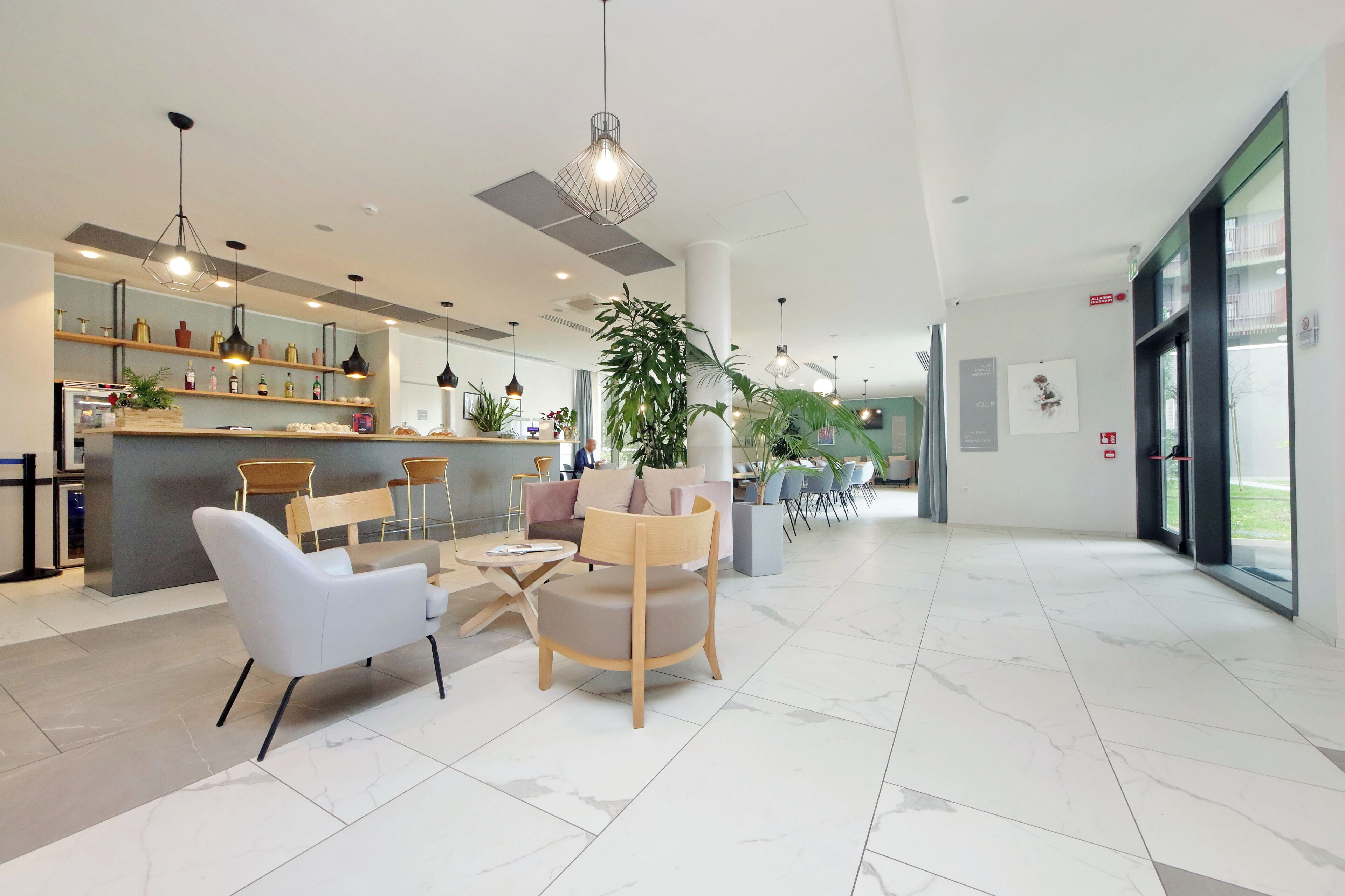 A modern hotel lobby with a bar area, seating arrangements, and large windows.