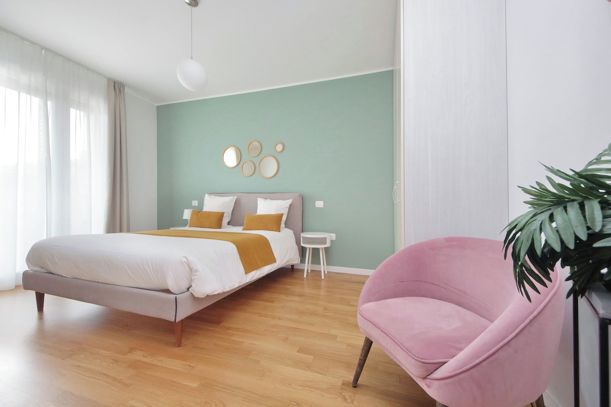 A modern bedroom with a bed, bedside tables, a chair, and a plant.