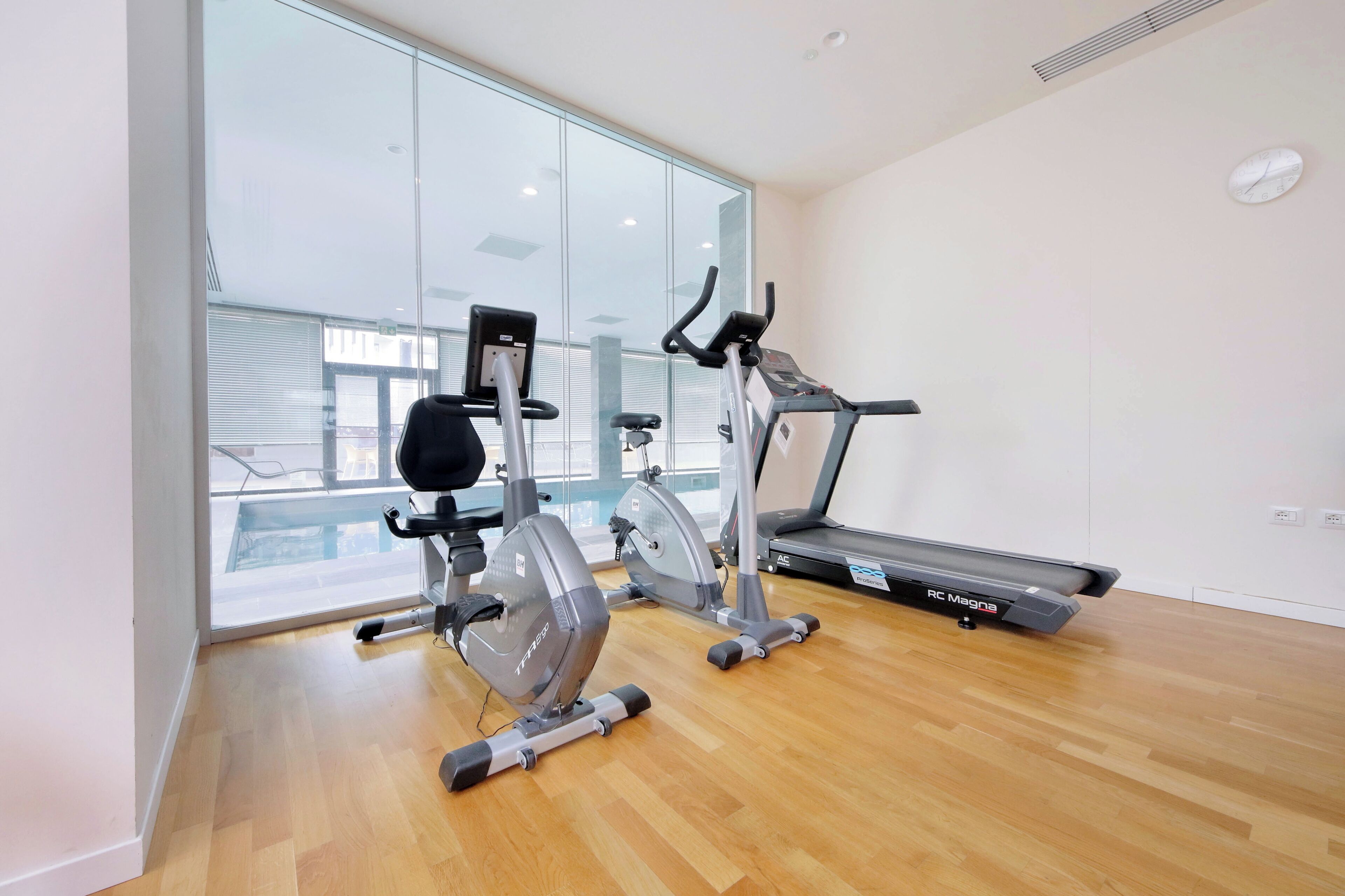 Een fitnessruimte met cardio-apparatuur, een loopband en een hometrainer.