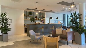 A modern hotel lobby with a bar area, seating arrangements, and potted plants. -  Quarto Verde Apartments (Bergamo)