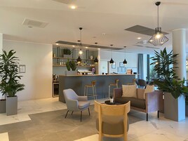 Una hall d'albergo moderna con un'area bar, posti a sedere e piante in vaso.