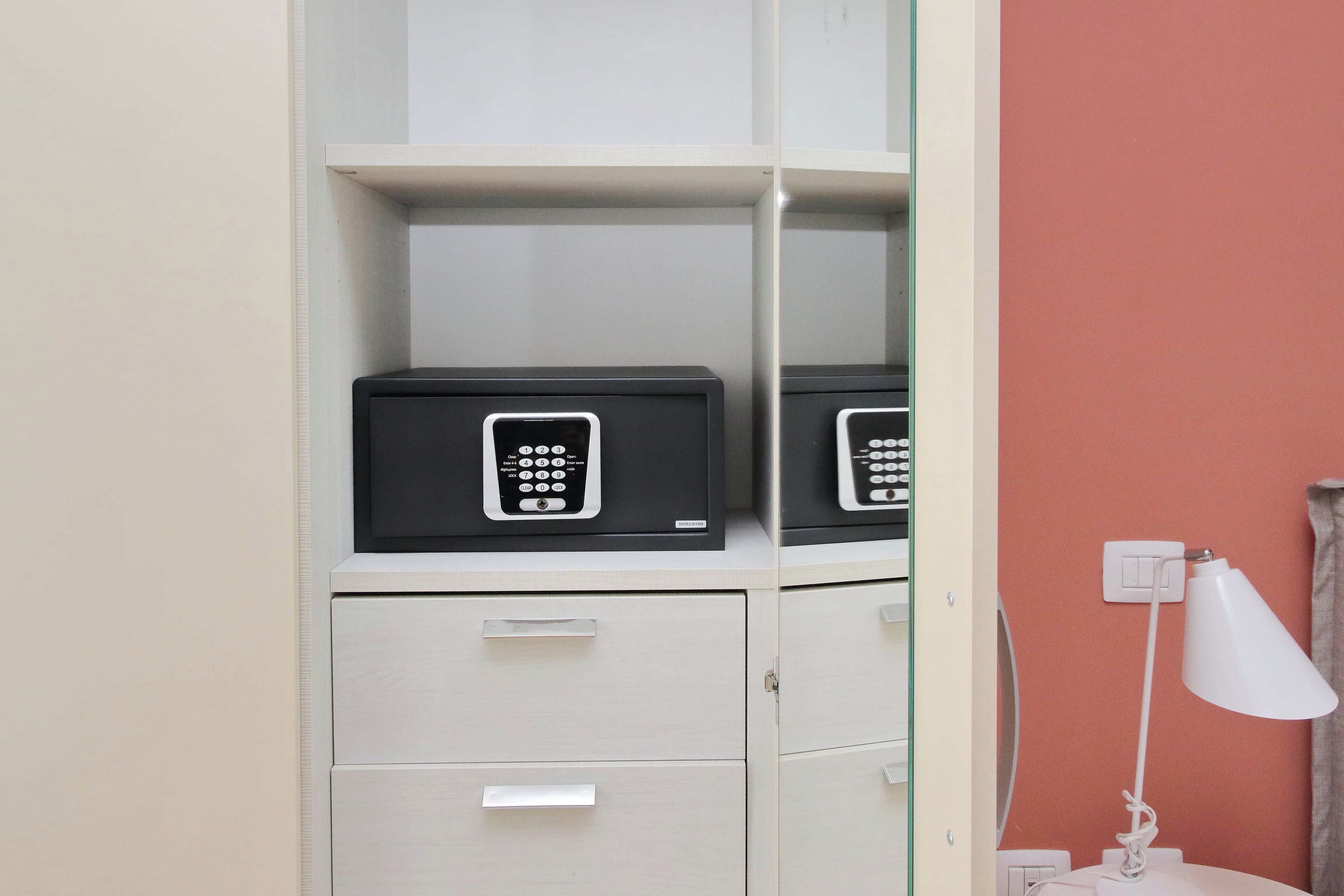 A room with a white filing cabinet, a desk lamp, and a red wall.