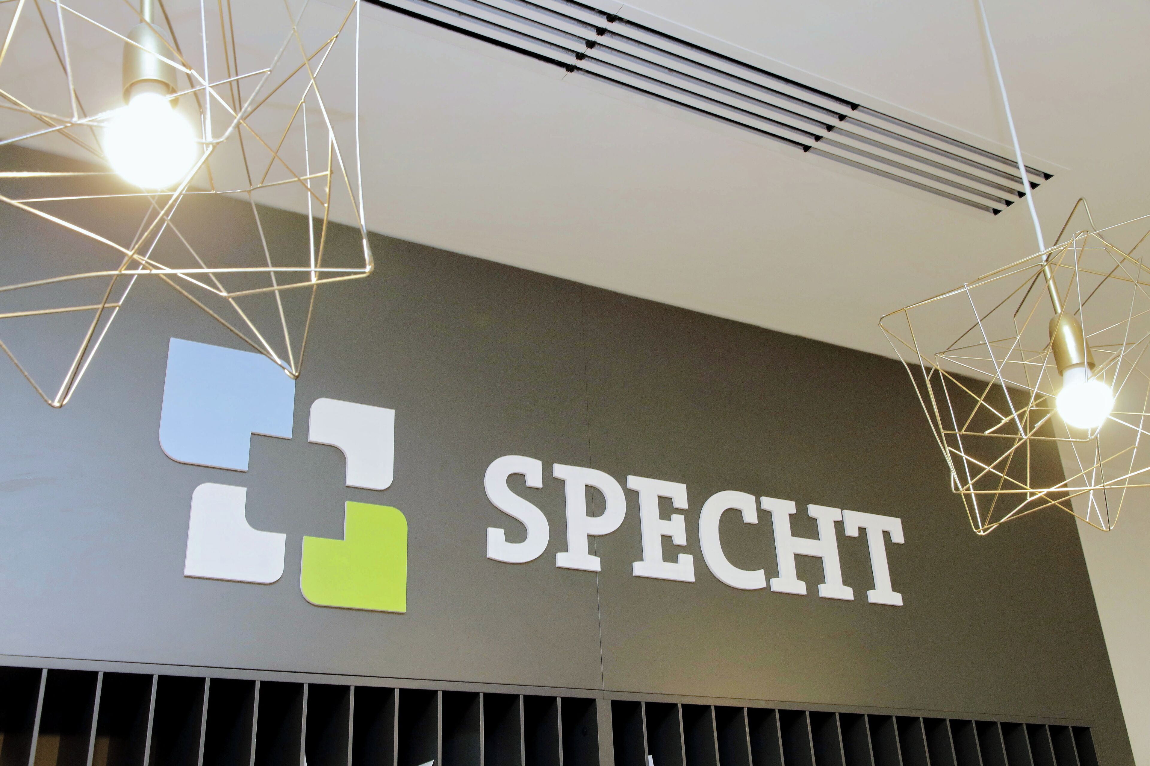 Ein Schild mit dem Wort 'SPECHT' und einem Logo in Blau, Weiß und Grün.