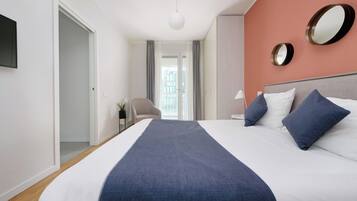 A hotel room with a bed, a chair, a nightstand, and a large window.