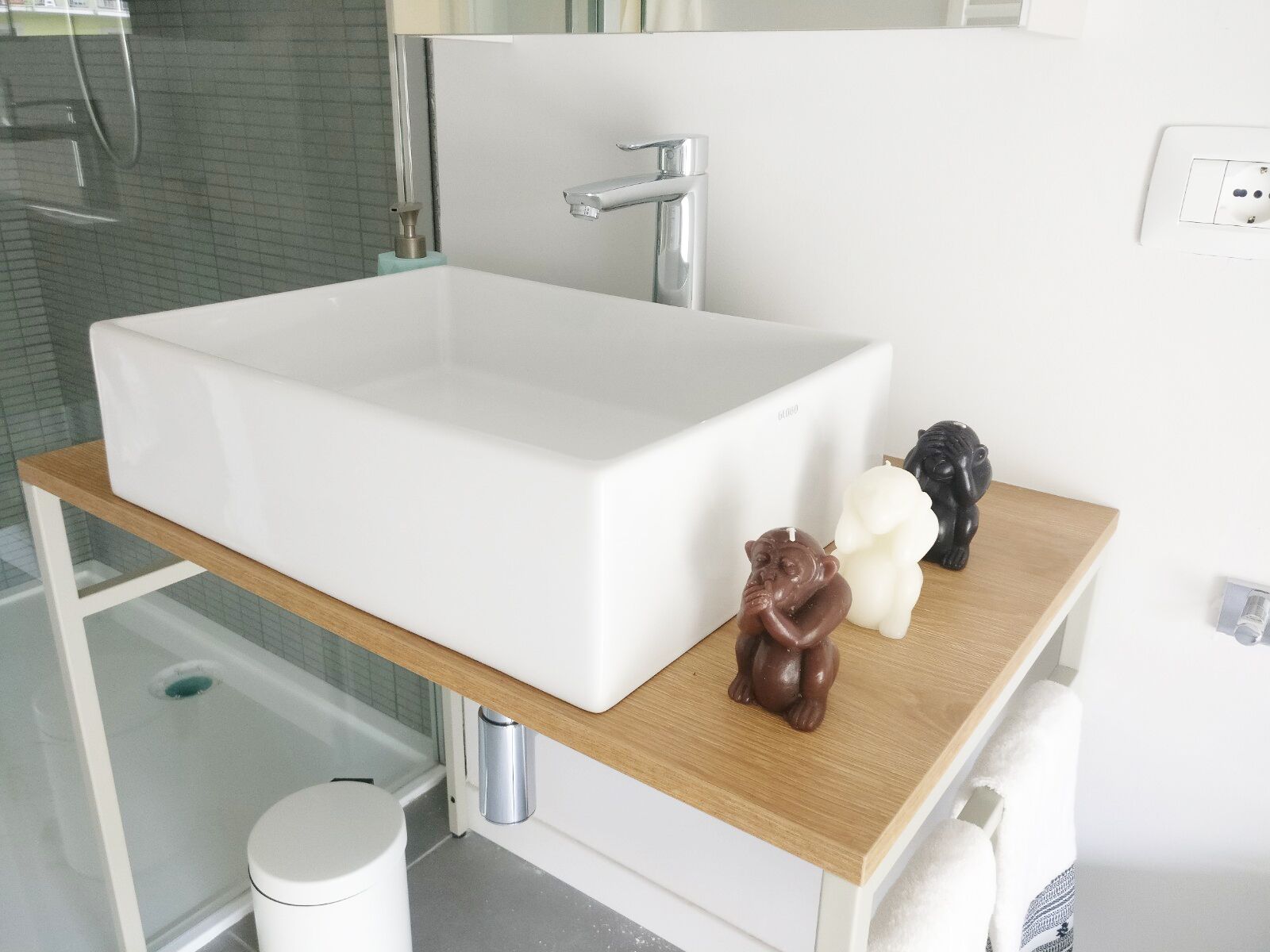A bathroom with a large white sink, a wooden vanity, and a mirror above it.