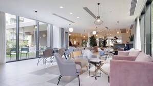 A modern hotel lobby with seating areas, large windows, and ceiling fans. -  Quarto Verde Apartments (Bergamo)