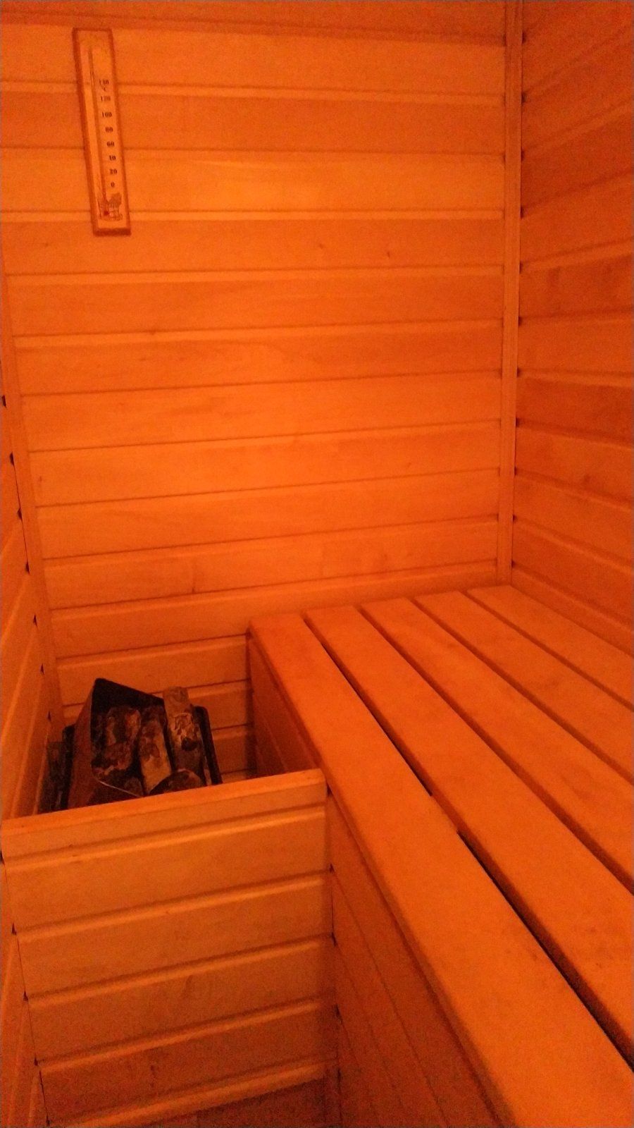 Un sauna avec des bancs en bois et un banc équipé d’un système de chauffage intégré.