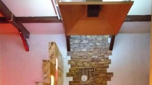 A cozy room with a stone accent wall, a wooden bench, a small table, and a bed with a pink headboard. - Shellman (Odesa)