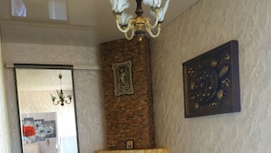 A living room with a fireplace, two white chairs, a round table, and a chandelier. - Shellman (Odesa)