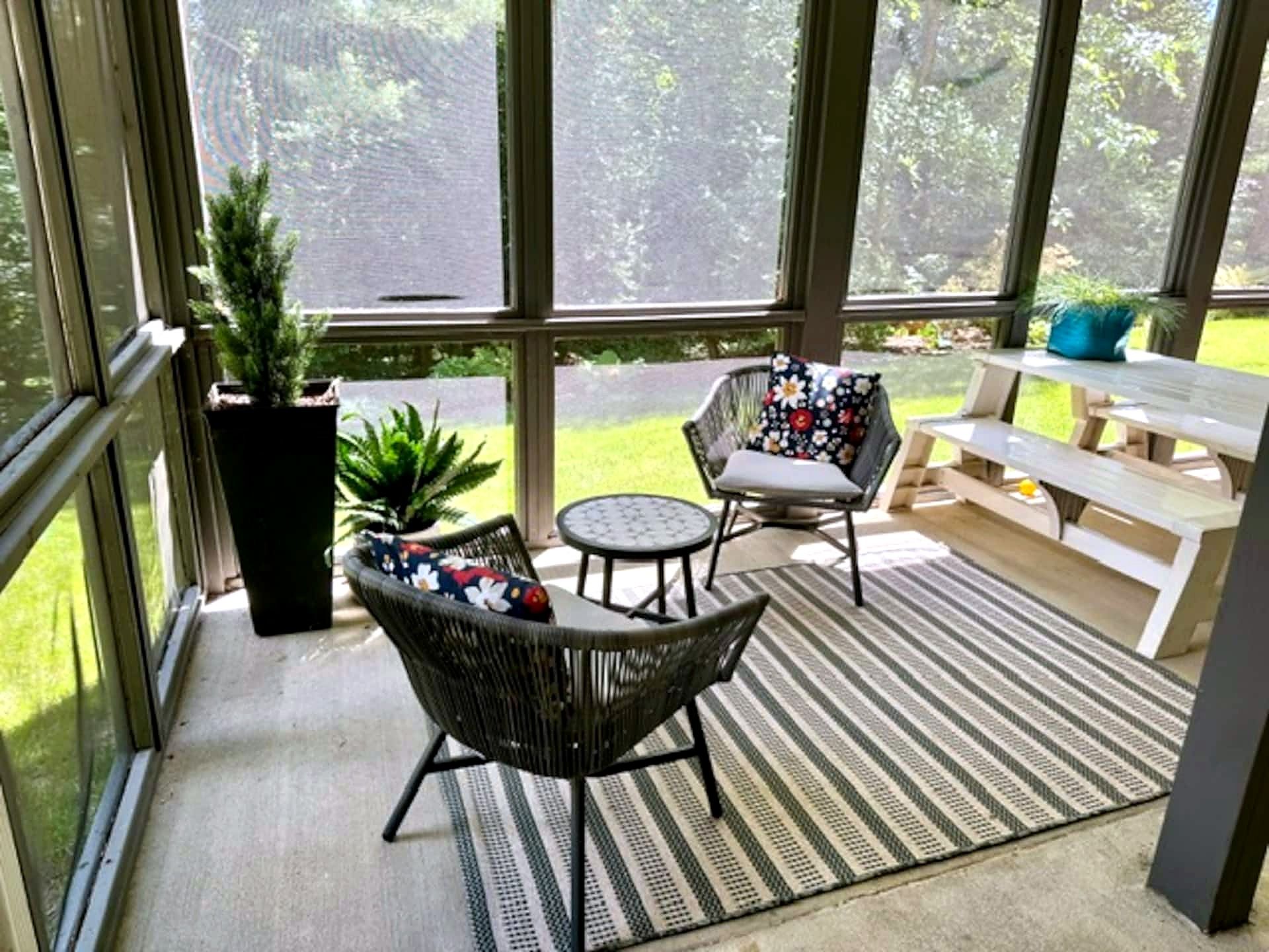 A sunlit patio with a seating area, including a bench and two chairs with floral cushions.