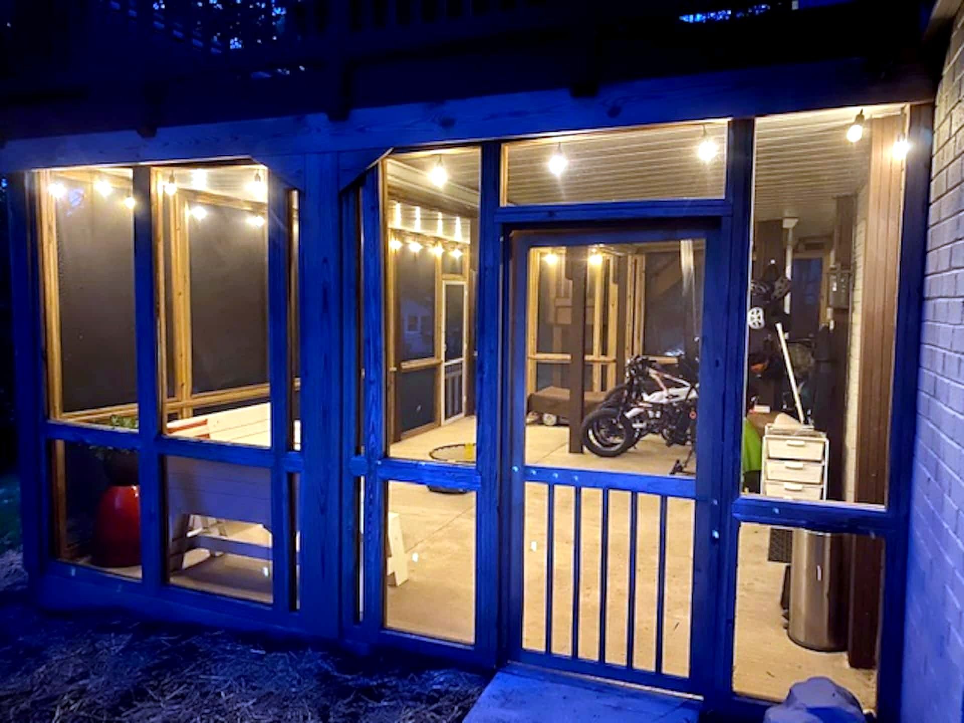 A building with multiple glass doors and windows, a motorcycle inside, and a trash bin outside.