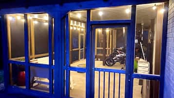 A building with multiple glass doors and windows, a motorcycle inside, and a trash bin outside.