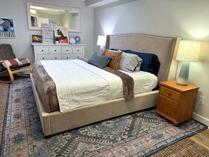 A bedroom with a large bed, a nightstand, a dresser, a chair, and a rug. - Private 1BR Suite w/ Own Entry · Walk to GMU (Fairfax)