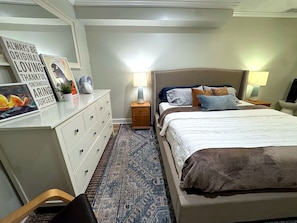 A bedroom with a bed, bedside tables, a dresser, a mirror, and a wall with motivational posters.