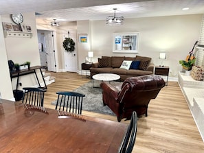 A living room with a brown leather sofa, a coffee table, and a dining table with chairs.
