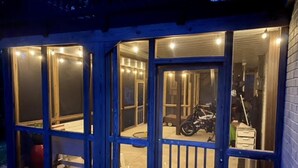 A building with multiple glass doors and windows, a motorcycle inside, and a trash bin outside.