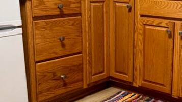 A kitchen with wooden cabinets, a coffee maker, a toaster, and a colorful rug on the floor.