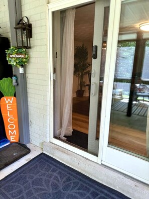 A sliding glass door entrance with a welcome sign, a potted plant, and a remote control on the wall. - Private 1BR Suite w/ Own Entry · Walk to GMU (Fairfax)