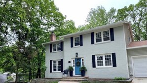 A two-story house with a blue front door, a brick chimney, and a well-maintained lawn.