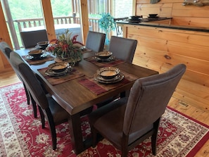 A wooden dining table set with plates, bowls, and a vase of flowers.