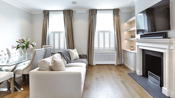 Ein modernes Wohnzimmer mit einer Couch, einem Glastisch, einem Kamin und einem an der Wand montierten Fernseher.