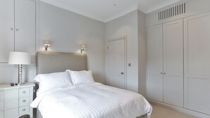 Ein Schlafzimmer mit Bett, Nachttischen, einer Lampe und einem Kleiderschrank.