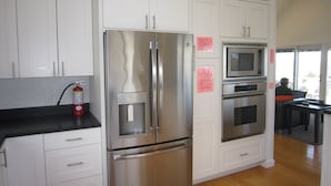 A modern kitchen with stainless steel appliances, white cabinetry, and a wooden floor.