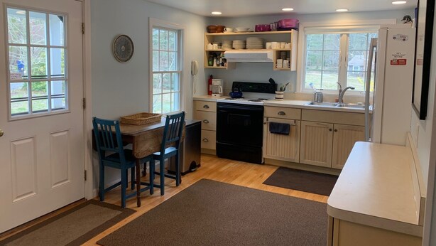 A compact kitchen with a dining area, wooden cabinets, a stove, and a refrigerator. - Less Than 1 Mile to Point of Rocks Beach (2186) (Brewster)