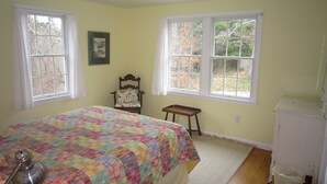 A bedroom with a bed, a chair, a small table, and two windows. - Less Than 1 Mile to Point of Rocks Beach (2186) (Brewster)
