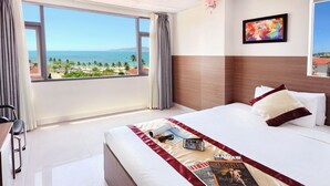 A hotel room with a large window offering a view of the beach and ocean. - Arise Hotel (Nha Trang)