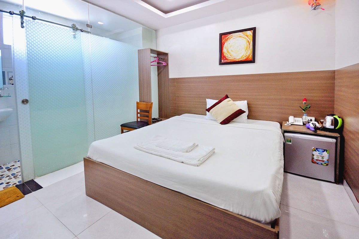 Une chambre d’hôtel équipée d’un lit, d’une table de chevet, d’un petit réfrigérateur, d’une douche et d’une salle de bain.
