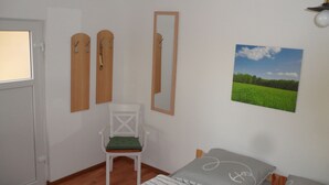 Un dormitorio con cama, una silla, un espejo y un cuadro en la pared.