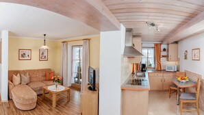 Un salon moderne avec un canapé, une table basse et un téléviseur. Il y a également un coin cuisine avec une table à manger et des chaises.