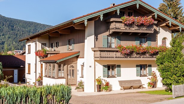 Un chalet tradizionale con balcone, persiane in legno e fioriere.