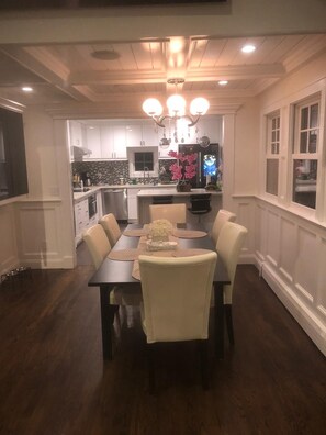 Enjoy meals in this classic dining area with a central table and six chairs, surrounded by a kitchen with modern appliances.