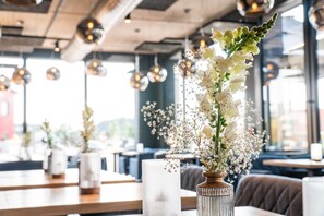 A restaurant interior with tables, chairs, and decorative vases with flowers.