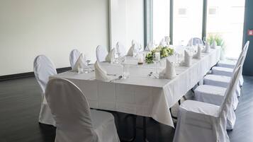 A long dining table with white tablecloth and chairs, set for a formal meal.