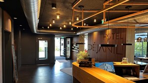Una moderna recepción con mostrador de madera, iluminación colgante y vistas al exterior.