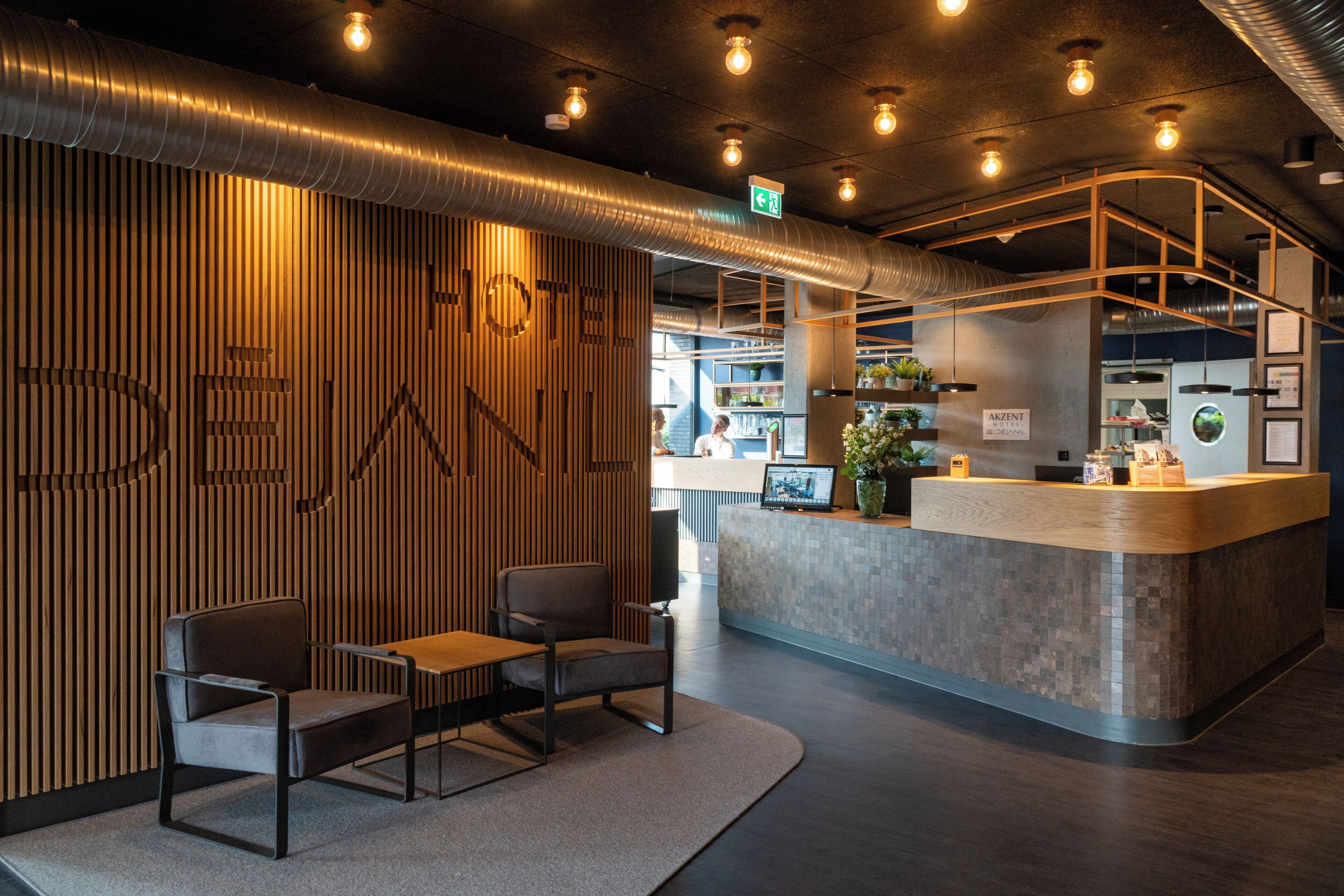 Zona de recepción de hotel con pared de madera, mostrador de recepción y asientos.