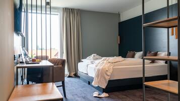 A hotel room with a bed, a desk, a chair, and a window with curtains.