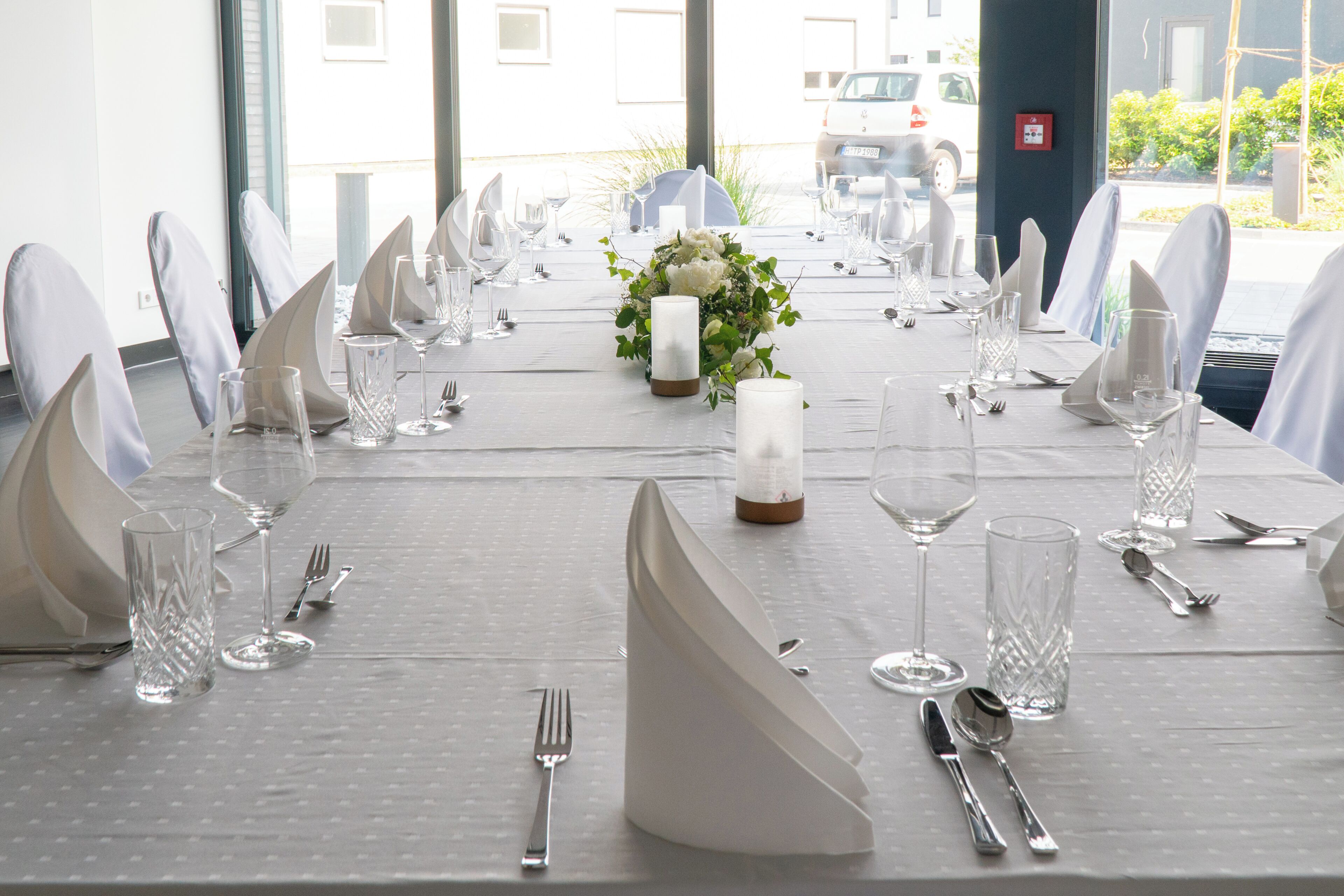 A table set for a formal event with white tablecloths, glassware, and silverware.