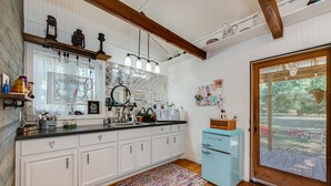 A kitchen with white cabinets, a black countertop, a vintage blue refrigerator, and a wooden ceiling. - Log Cabin - TINY HOUSE on acreage (Montgomery)