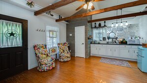 A kitchen with wooden beams, a ceiling fan, and a window with a star design. - Log Cabin - TINY HOUSE on acreage (Montgomery)