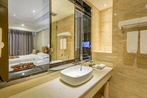 A hotel bathroom with a large mirror, a sink, and a shower area. - Golden Phoenix Hotel Luohe (Luohe)