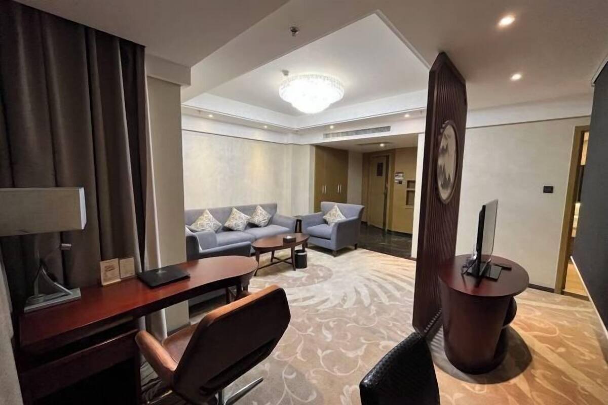 Una habitación de hotel con escritorio, silla, sofá y una alfombra grande.