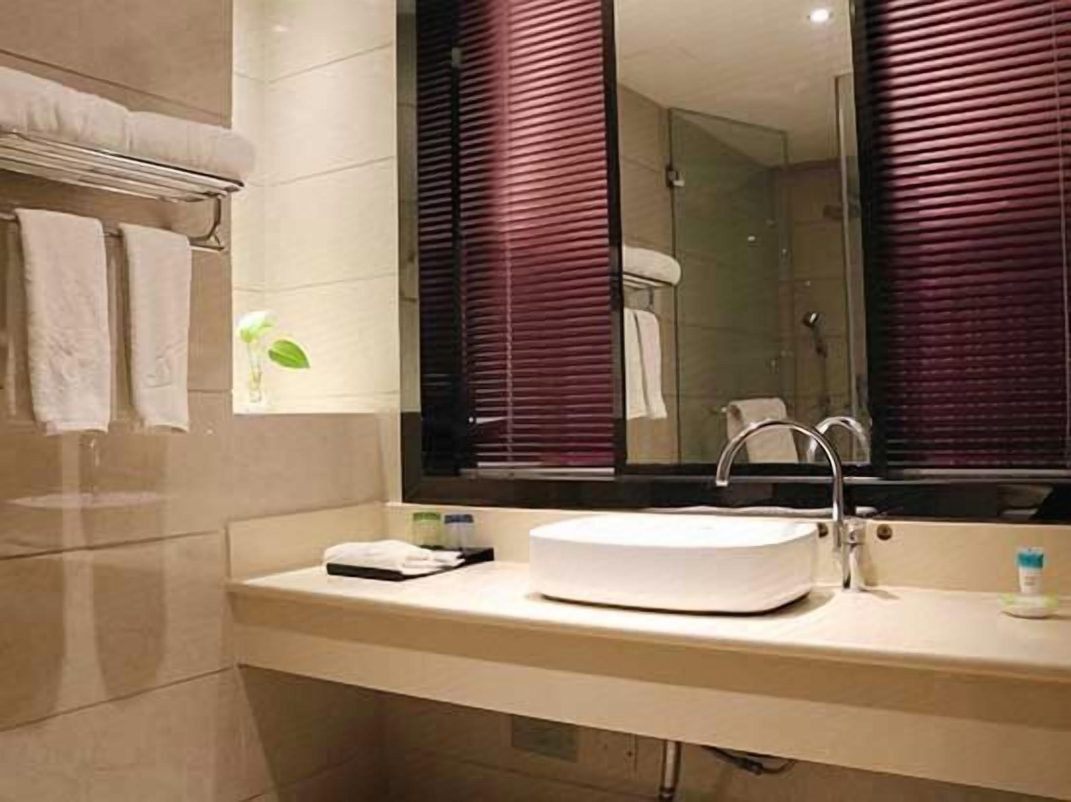 A modern bathroom with a large mirror, a round sink, and a glass shower enclosure.