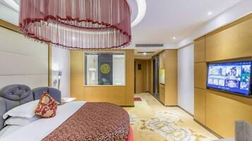 A hotel room with a bed, a television, a desk, and a large mirror.